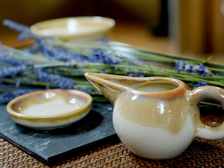 Pouring pot and trinket dish on table with lavender in background