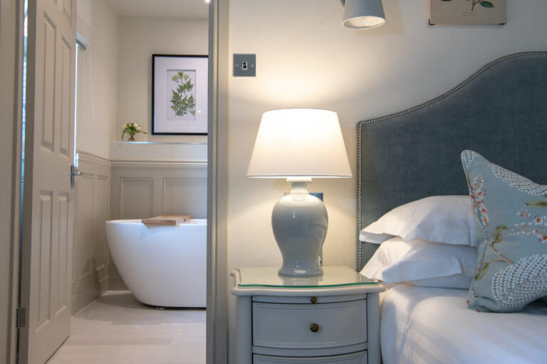View into the Roof terrace suite bathroom with bedside table and bed in view