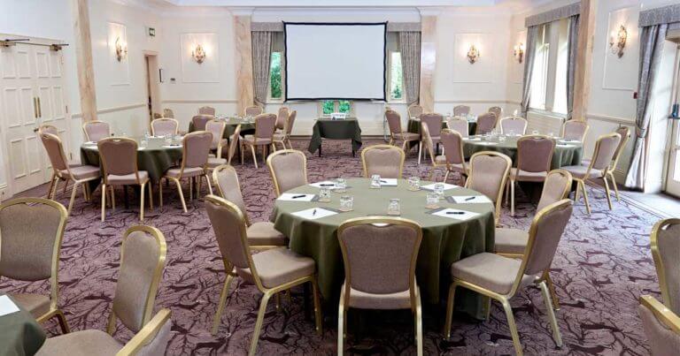 Conference room set up with round tables and a projector screen