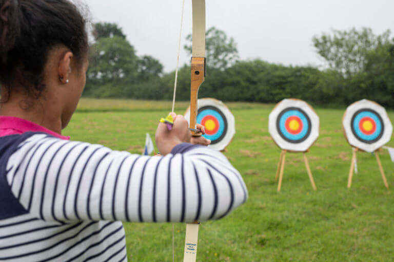 Woman shooting bow and arrow in archery activity