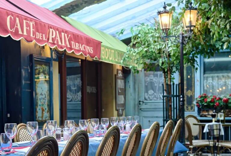 Interior of French restaurant with street café theme and long table with wine glasses prepared for service