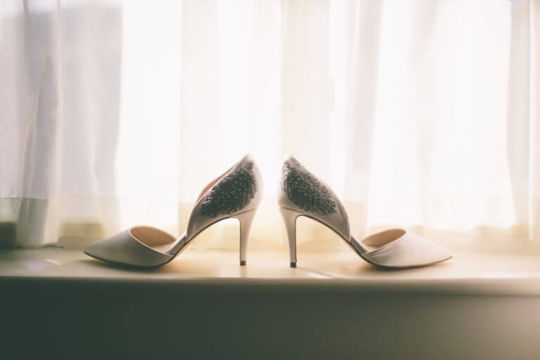 A pair of white satin bridal court shoes with sequins on the heel