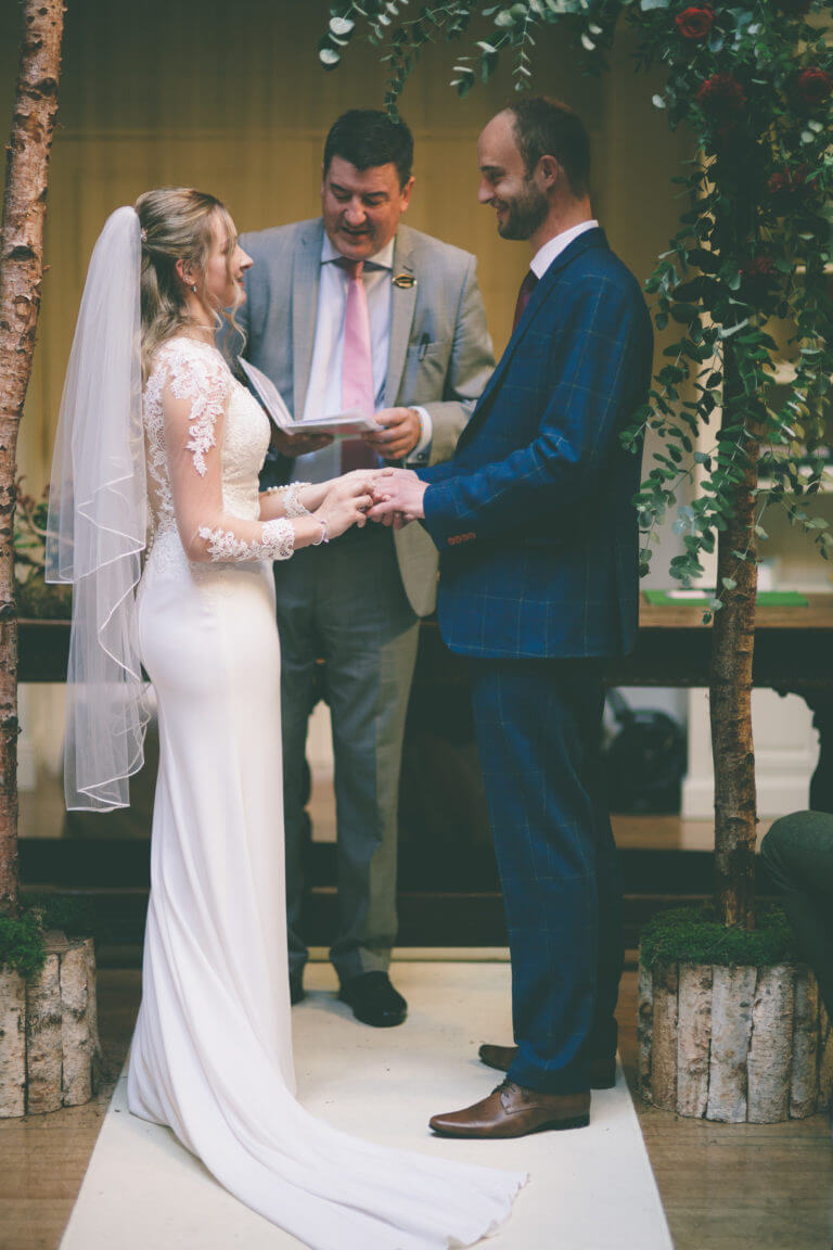 A couple saying their vows with the registrar during a wedding ceremony in the lounge at Careys Manor.