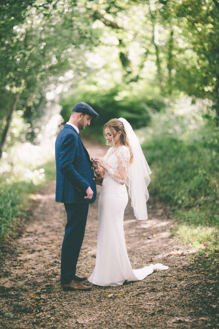 Bride and groom stand together on woodland path
