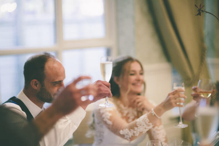 Bride and groom toast with champagne at wedding table
