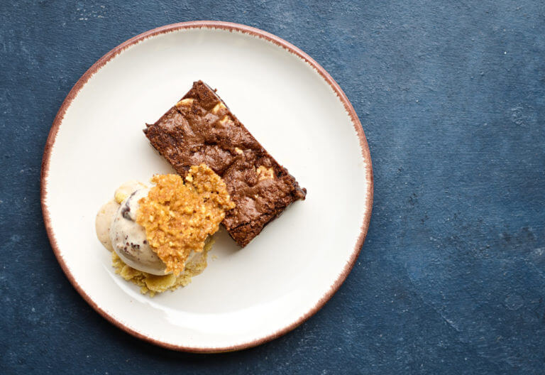 Double chocolate brownie dessert served with ice cream and a brittle crumb on a plate