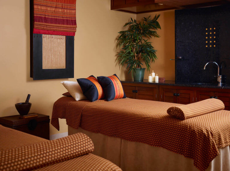 A massage couch within a treatment room at SenSpa dressed with Thai patterned fabrics and Thai silk cushions.