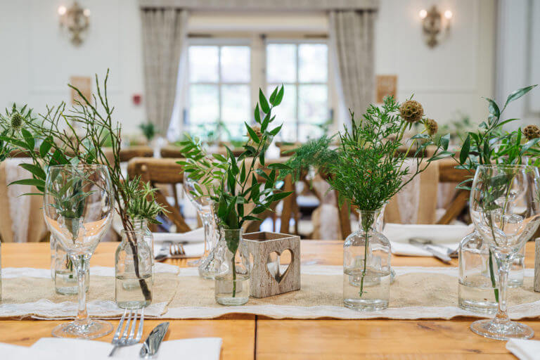 A tablescape with glass vases filled with foliage and dried flowers.