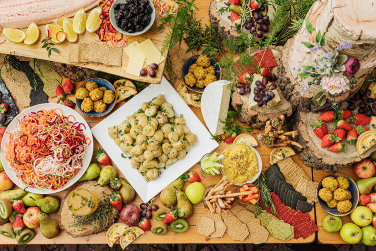 An indulgent wedding 'grazing board' buffet with salads, fruits, cheeses, crackers, a side of salmon and a rustic wedding cake.