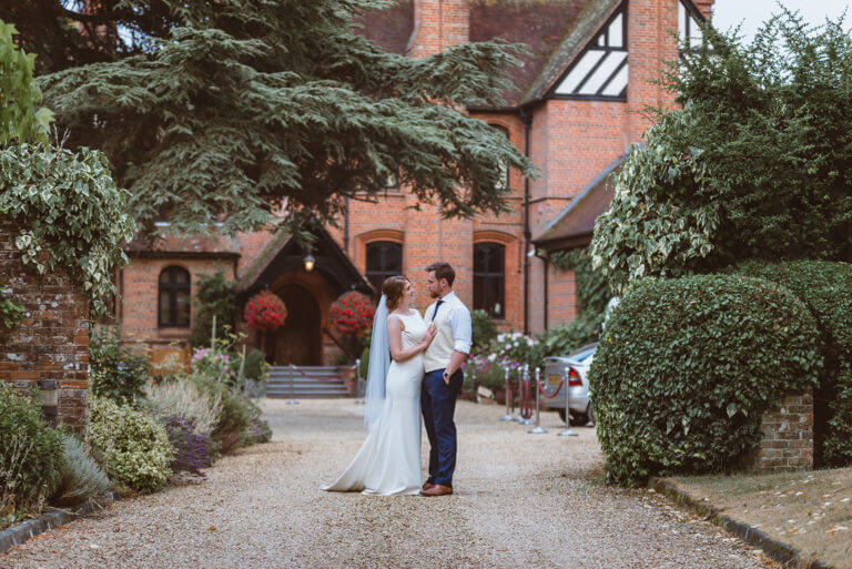 Bride and groom stand looking at each other outside Careys Manor Hotel & SenSpa 