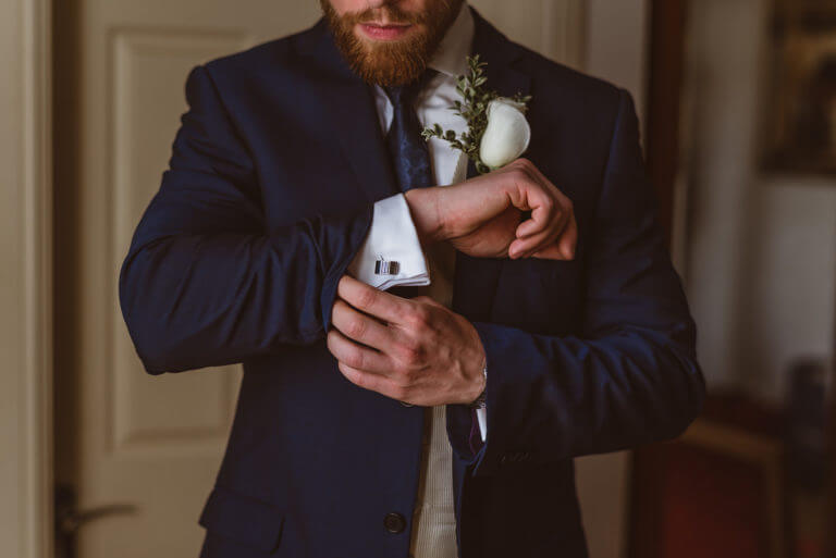 Close up shot of groom fixing cuffs on wedding suit