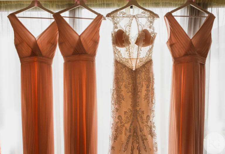 Wedding dress and three bridesmaid dresses hang from window