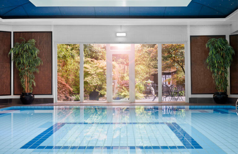 Swimming pool at Careys Manor Hotel & SenSpa with large windows and warm sunlight shining through