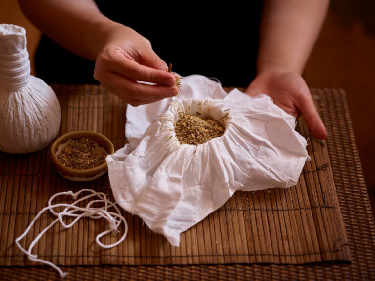 a SenSpa therapist preparing a Thai poultice filled with fragrant herbs