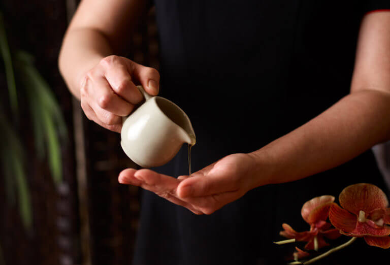 spa massage oil being poured into a therpist's hand