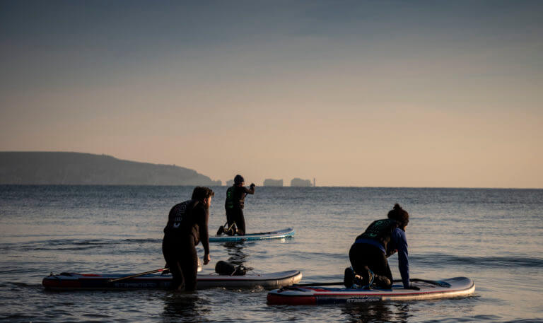 Three people stand up paddle boarding in the Solent.