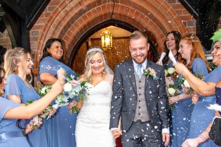 Wedding couple having confetti thrown at them outside Careys Manor