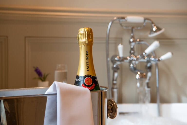 freestanding bath with a bottle of Champagne at Careys Manor Hotel & SenSpa