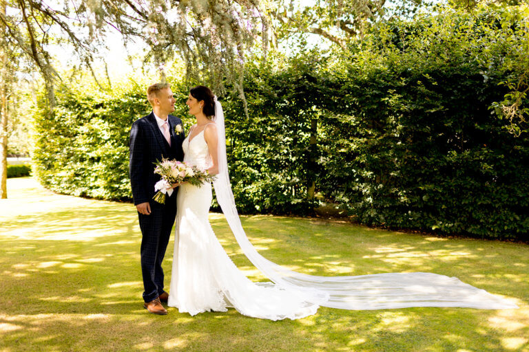 Bride & Groom Hayley & Mike pose together in the garden of Hampshire wedding venue Careys Manor Hotel