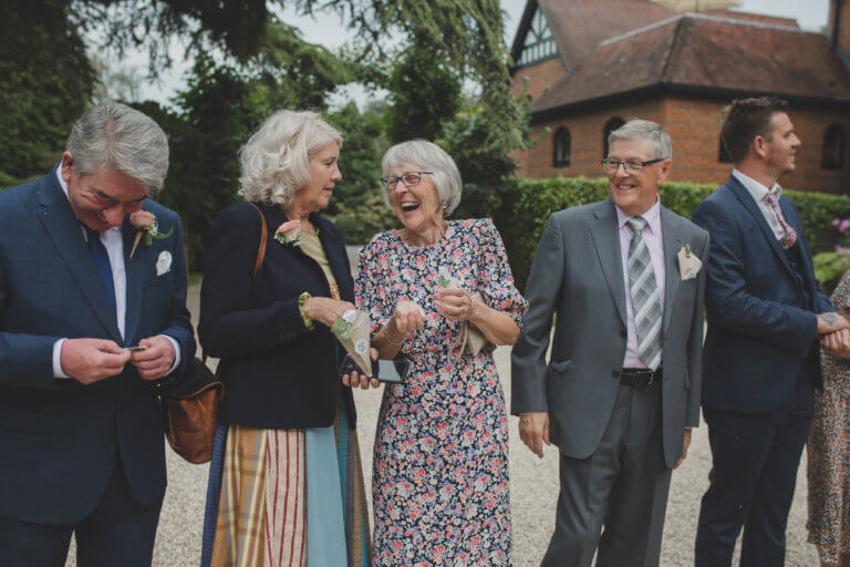 Guests smile and laugh together outside hampshire wedding venue Careys Manor Hotel