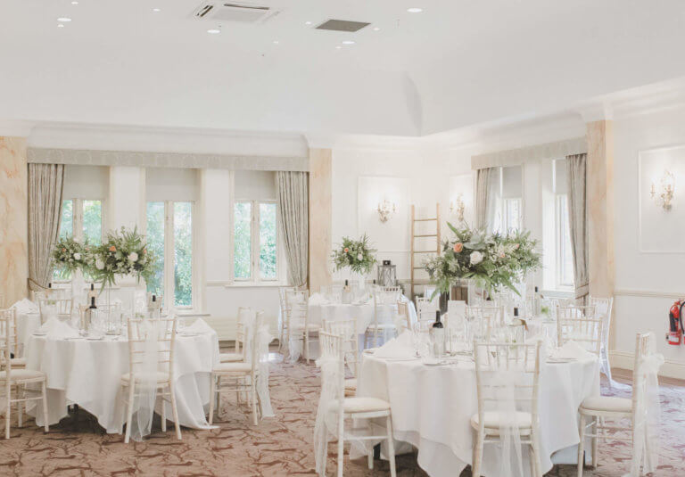 Wedding breakfast set with round tables and white flowers at Careys Manor Hotel, Hampshire wedding venue