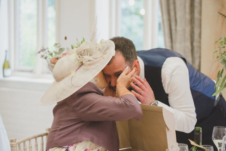 The Groom receives a big kiss on the cheek from the mother of the bride at Hampshire wedding venue Careys Manor Hotel