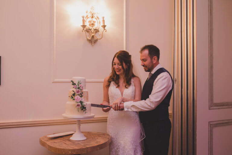The Bride and Groom cut the wedding cake at Hampshire wedding venue Careys Manor Hotel