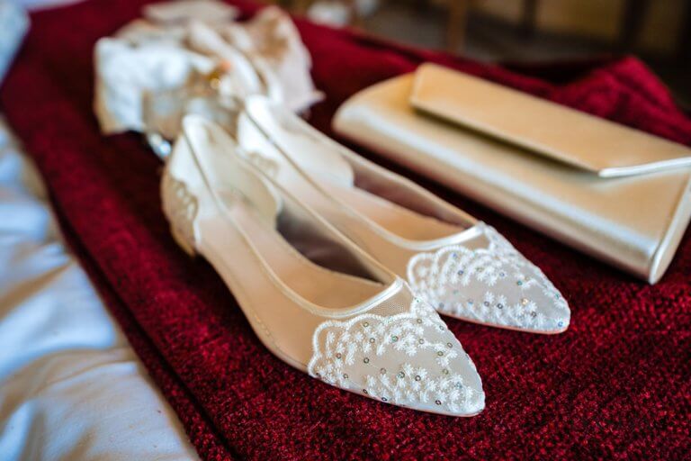 The bride's ballerina shoes and cream clutch bag