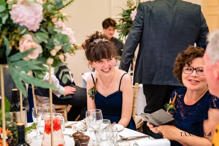 Guest smiles while seated during the wedding breakfast
