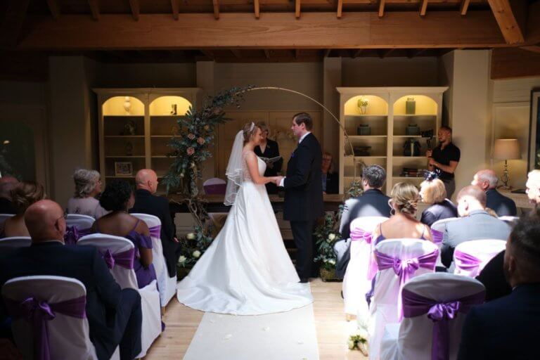 Bride and groom stand at their ceremony with their guests watching on