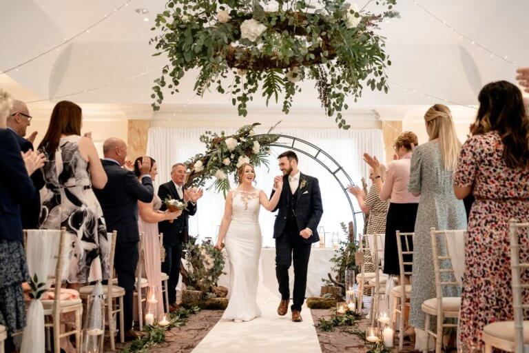 The bride and groom leave the ceremony room while their guests clap