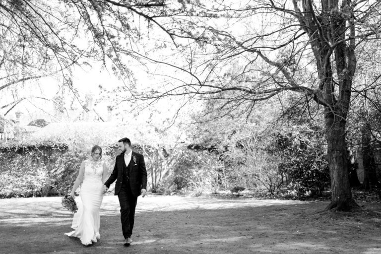 The bride and groom stroll hand in hand in the garden