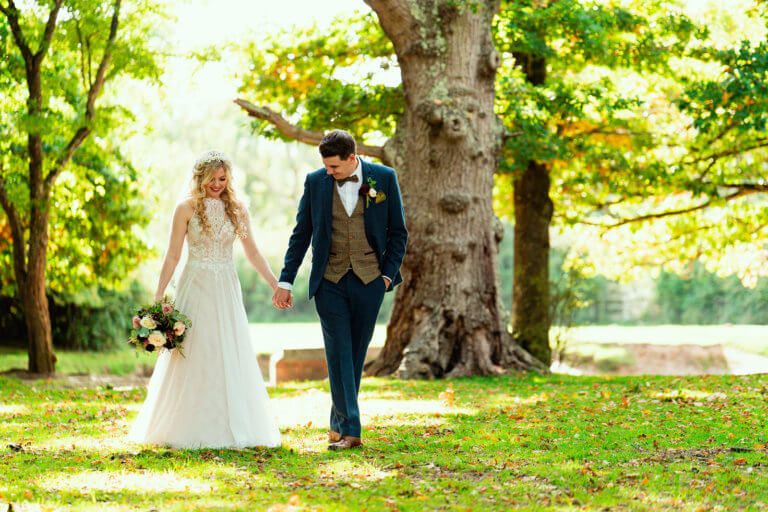 Bride and Groom walk hand in hand through the gardens