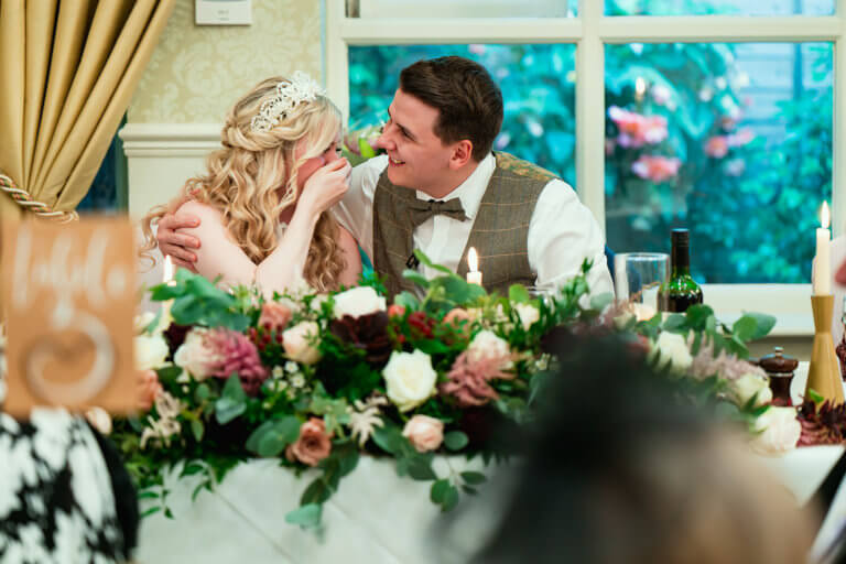 The bride laughs with the groom at the end of his speech