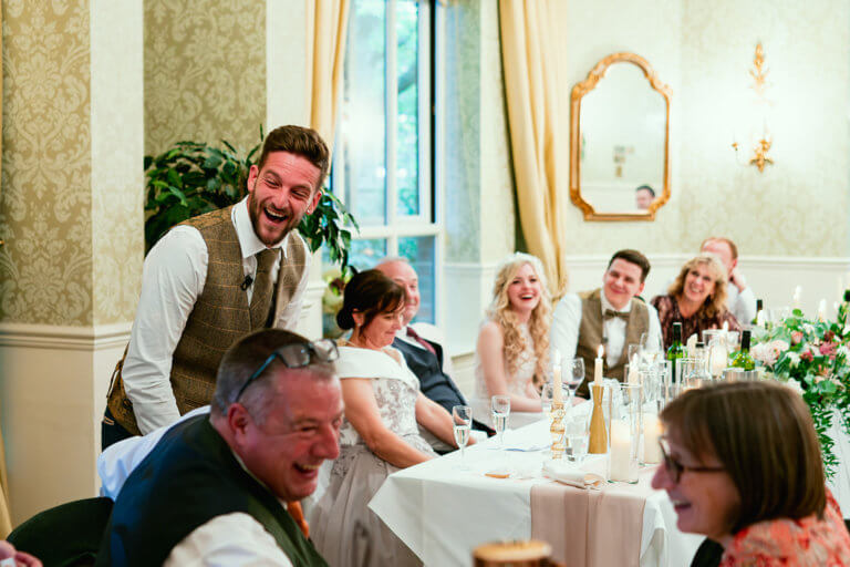 The best man and guests laugh during his speech