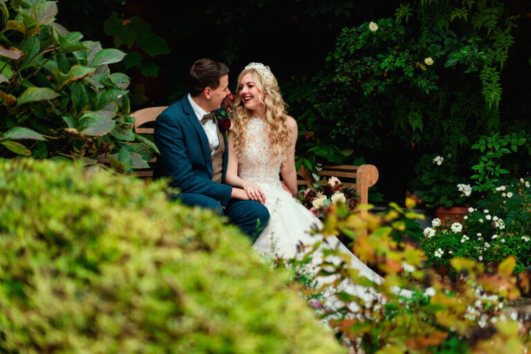 The married couple sit on a bench in the garden and smile together