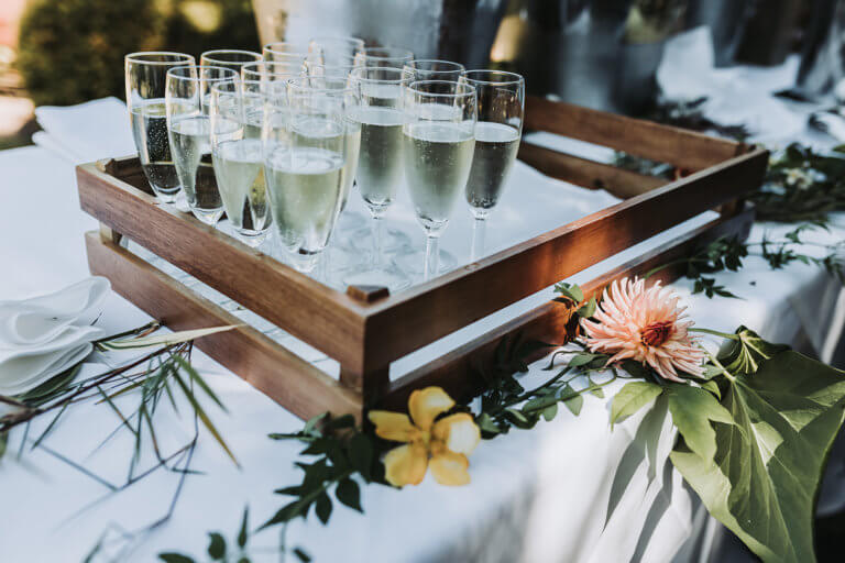 A tray of sparkling wine surrounded by foliage