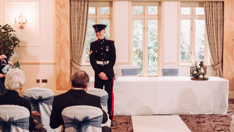 The groom stands by the registrars table talking to guests before the wedding ceremony