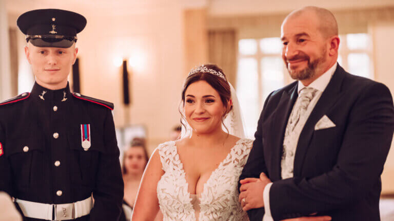 The father of the bride stands with the couple in front of the registrars table