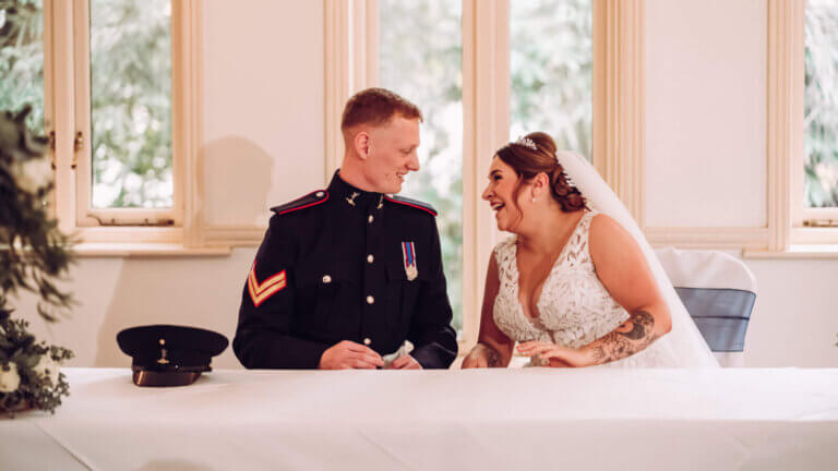 The couple smile at each other before signing the register