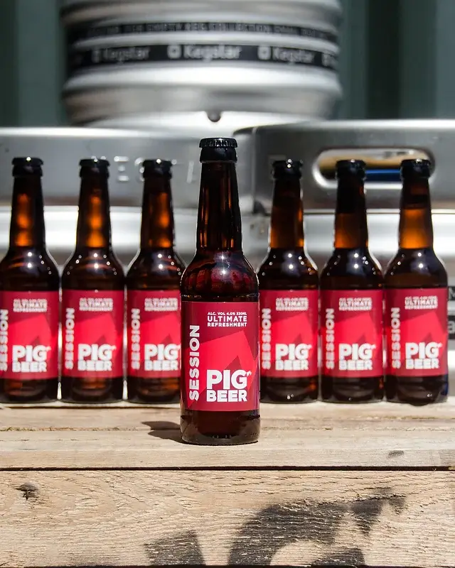 Line up of Session Pig Beer on wooden crate with kegs in the background
