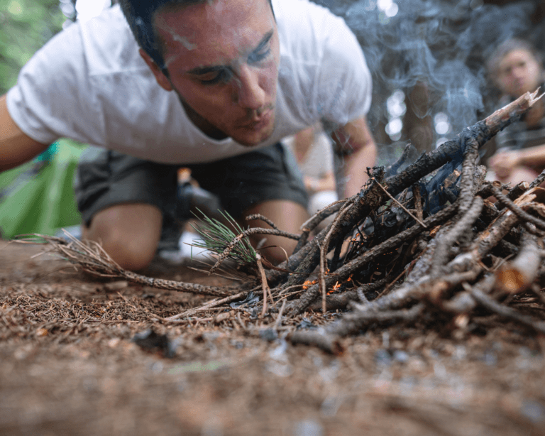 Man learning survival skills in the forest starting a fire