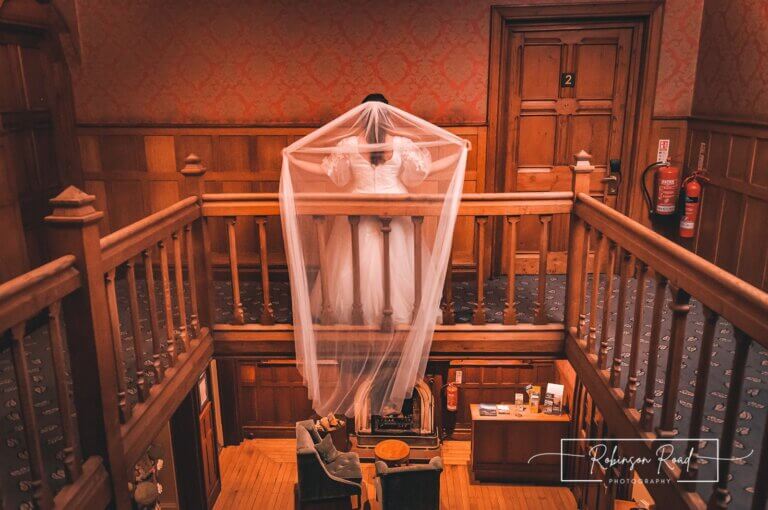 Bride drops veil over staircase bannister at Careys Manor Hotel & SenSpa wedding venue in The New Forest