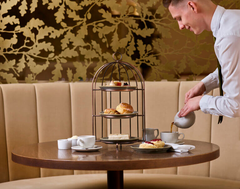 Afternoon tea being served by a waiter at Cambium Restaurant, Careys Manor Hotel & SenSpa