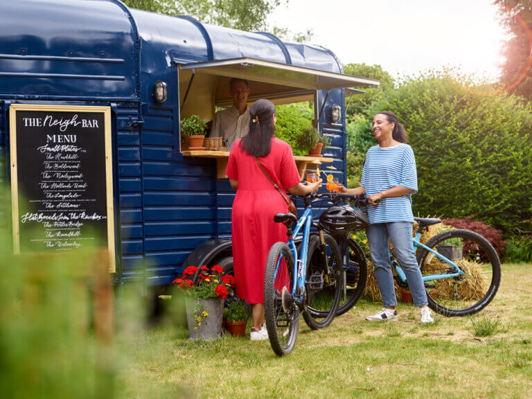 Two women with bikes ordering from an outdoor bar