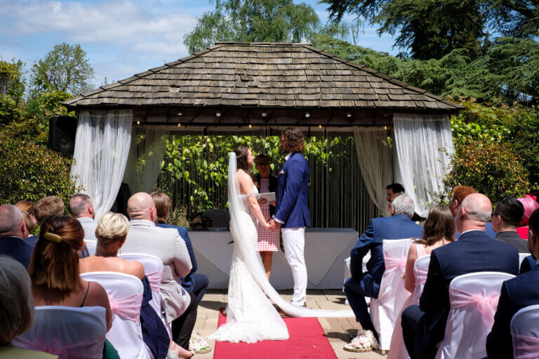 Bride and groom gaze at each other, holding hand s during the wedding ceremony.