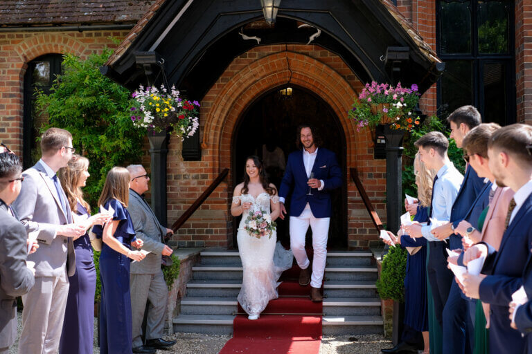 The bride and groom walk down the steps of the hotels main entrance to their waiting guests