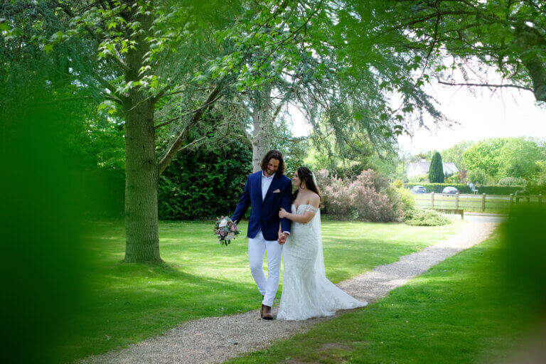 The bride and groom walking hand-in-hand through the gardens