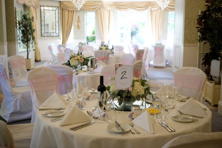 table setting for the wedding breakfast showing a low arrangement of white flowers