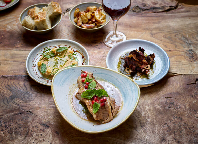 Variety of seasonal dishes and glass of red wine served on wooden table at Cambium Restaurant, Careys Manor Hotel & SenSpa, Brockenhurst